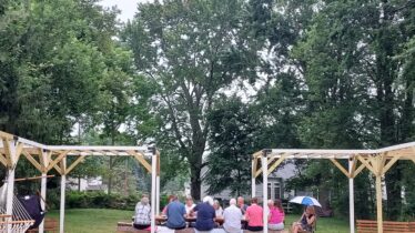 small group sits at picnic table outside
